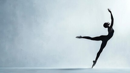   A woman in black leotard performs a ballet move on a white surface against a gray backdrop