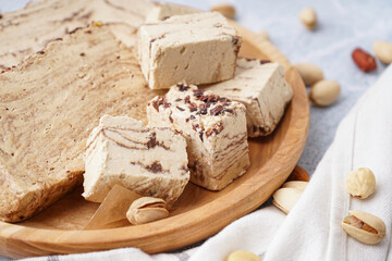 Plate with pieces of tasty marble halva on light background