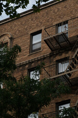 A brick building showcases iconic fire escapes against its facade. The metal staircases add an urban charm, capturing the essence of city architecture and everyday life in a bustling environment