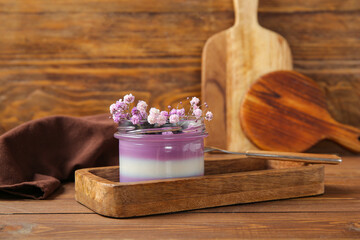 Glass of panna cotta with blueberry and beautiful gypsophila flowers on wooden background