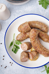 Plate of tasty homemade sausages on light background