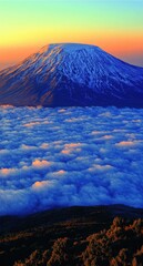 Stunning View of Mount Kilimanjaro at Sunrise with Snow-Capped Summit Rising Above Clouds in Tanzania - Majestic Mountain Landscape Photography