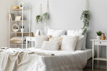 Cozy bed with soft pillows in interior of light bedroom