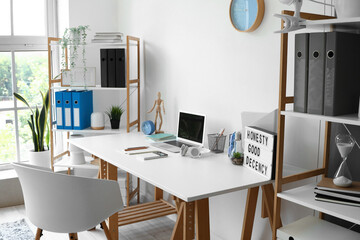 Interior of light office with modern workplace and shelving units