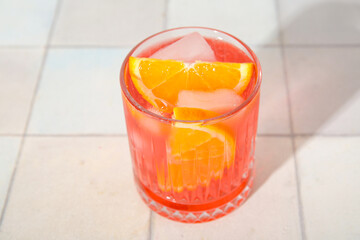 Glass of cold Negroni cocktail on light tile background