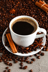 Cup of tasty coffee with cinnamon and beans on table