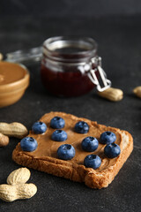 Toast with peanut butter and blueberries on black background