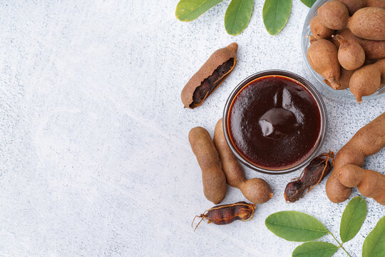Bowl with tasty tamarind jam and fruits on white background