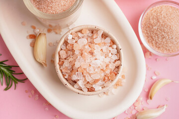 Bowls with Himalayan pink salt and garlic on pink background