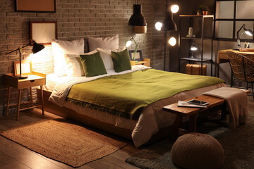 Interior of stylish bedroom with green blanket on bed and glowing lamps at night