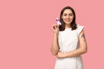 Pretty young woman with light purple ribbon on pink background. Testicular cancer awareness concept