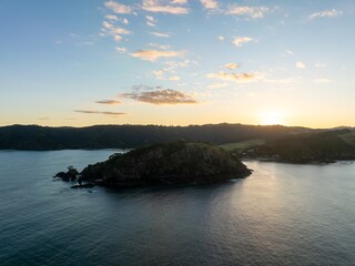 Coastal sunrise over Matauri Bay. Rocky outcrop silhouettes against the soft light. Peaceful morning scene. Matauri Bay, Kaeo, Northland, NZ
