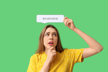 Excited young woman holding speech bubble with text REMINDER on green background