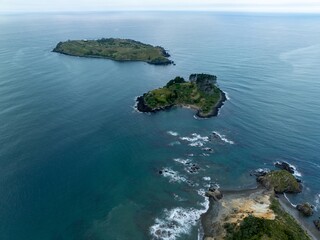 High-angle view of two small islands in a calm ocean. Tranquil coastal scenery. Mahinepua Peninsula, Kaeo, Northland, NZ