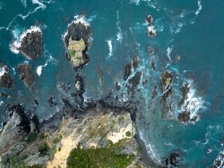 High-angle view of crashing waves against rocky coastline. Ocean water and rocks meet. Coastal landscape. Mahinepua Peninsula, Kaeo, Northland, NZ