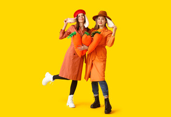 Funny friends with toy carrots and bunny ears trying to hear something on yellow background. Easter...