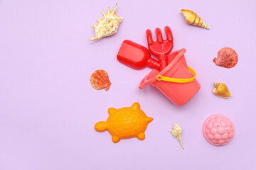 Set of beach accessories for children and seashells on lilac background