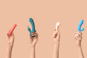 Female hands with different vibrators on brown background