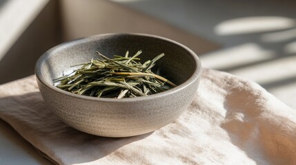 Intricate arrangement of loose kukicha green tea nestled in a simple bowl on a rustic cloth with soft sunlight enhancing the details