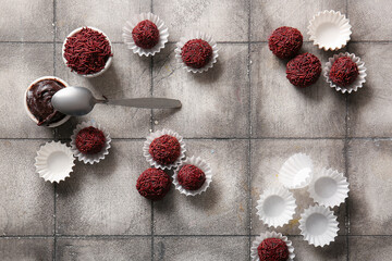 Delicious chocolate truffles with paper cups and bowl of chocolate paste on grunge tile background