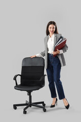 Beautiful businesswoman with folders and chair on light background