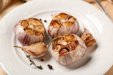 Plate with baked garlic, peppercorns and thyme, closeup