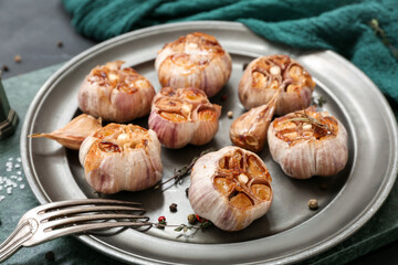 Plate with baked garlic, peppercorns and thyme, closeup