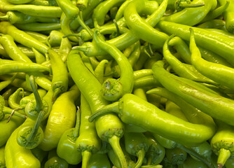 Raw green peppers on a supermarket counter.