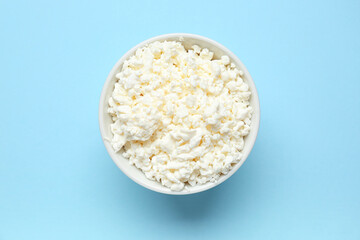 Bowl with fresh cottage cheese on blue background