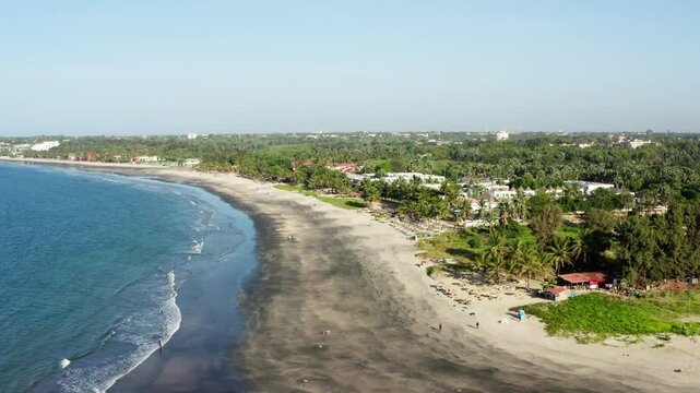 Aerial shot of a black sand beach on gambian coastline with hotels and local restaurants, Gambia, West Africa, 4K