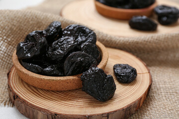 Plate with dried prunes on sack cloth background, closeup