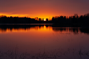 Sunset colours reflected from a calm lake in spring in Western Finland