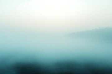 Misty morning landscape, serene teal fog over water.