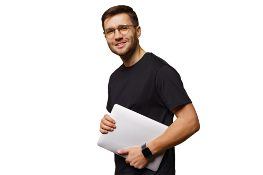 Young man in casual attire smiling while holding a laptop and posing against a plain background
