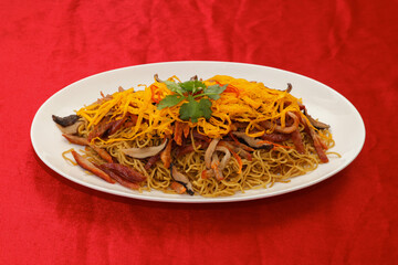 A vibrant plate of colorful fried noodles topped with vegetables, garnished with fresh herbs,...