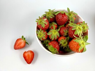fresh ripe delicious strawberries in a white bowl on white background