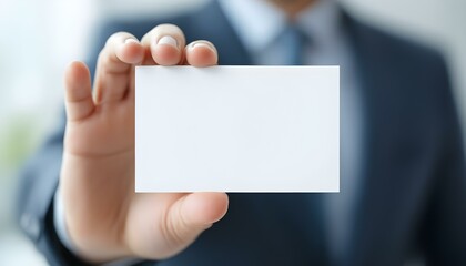 A hand holding a blank white card, close-up focus, with a blurred professional background, creating a clean and minimalistic look.
