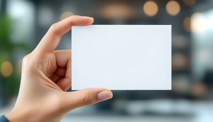 A hand holding a blank white card, close-up focus, with a blurred professional background, creating a clean and minimalistic look.