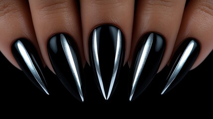 Close-up of stylish black and silver stiletto nails on dark background.