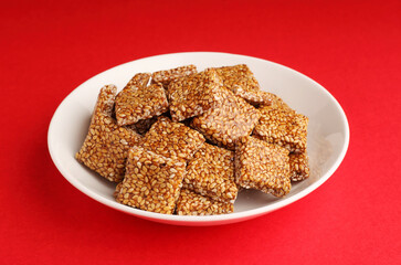 Sesame seed jaggery chikki or til ke chkki and tilgul or til gul ladduchikki served in bowl for Makar Sankranti Festival in India