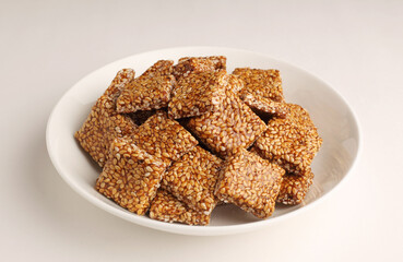 Sesame seed jaggery chikki or til ke chkki and tilgul or til gul ladduchikki served in bowl for Makar Sankranti Festival in India
