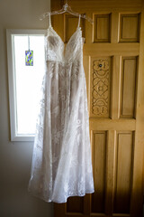 Elegant white bridal dress hanging in front of wood door