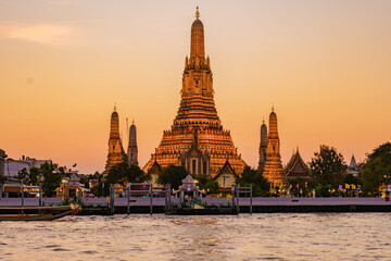Golden light bathes Wat Arun, the Temple of Dawn, as dusk descends over Bangkok. The majestic...