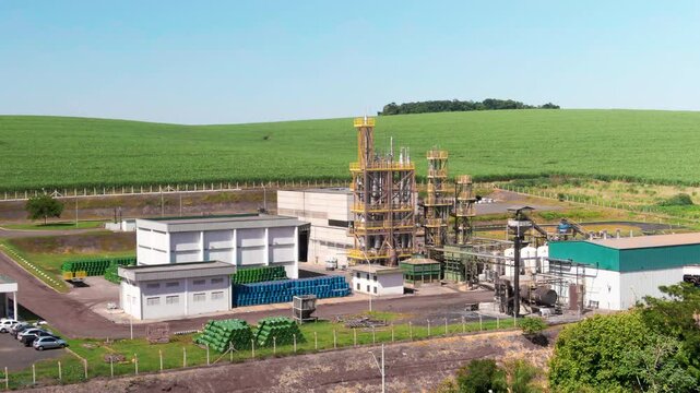 Aerial view of small refinery located in between a sugarcane plantation field during afternoon.