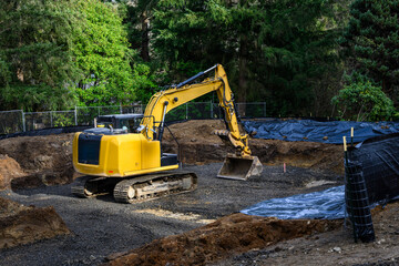 New home construction in residential neighborhood re-development, heavy equipment excavator digging out foundation, crushed rock gravel as base layer to build stable foundation
