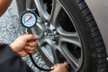 Hand car mechanic holding car tire pressure check equipment tool to checking low tire pressure...