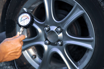 Hand car mechanic holding car tire pressure check equipment tool to checking low tire pressure...