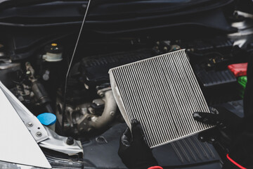 Car care maintenance servicing technician or auto mechanic holding car air conditioner filter for...