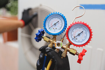 Electrical technician conditioning using manifold gauge measuring tool checking refrigerant pump...