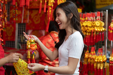 Obraz premium Young Asian Women Shopping for beautiful red ornament Offerings Outdoors market